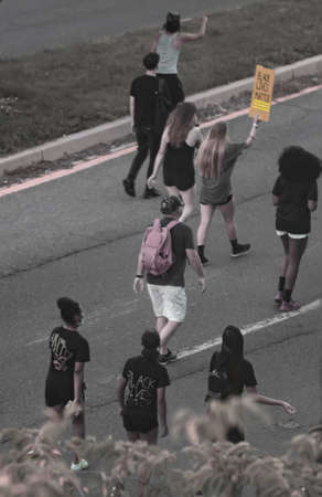 Maryland/USA 07/04/2020: Peaceful Black Lives Matter demonstration. Young men and women from all races walked to protest racism in USA. A blonde protester is holding a BLM banner.のeditorial素材