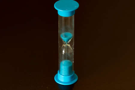 An abstract image featuring a single hourglass with sand particles flowing, This photo can be used...