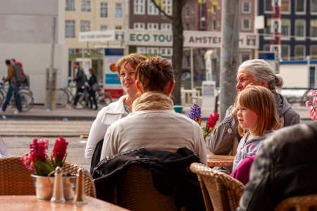 Amsterdam, Netherlands 05/15/2010: Three generations of women in a family are sitting around a table at a cafe in Amsterdam. They are  talking and laughing. Grandma sits next to her granddaugher.のeditorial素材