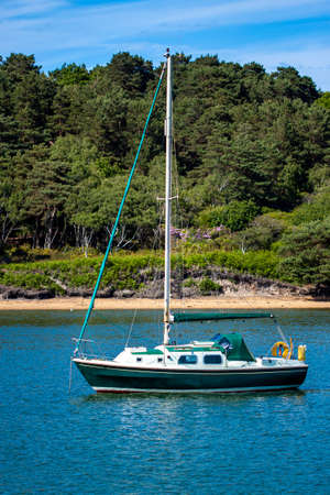 Isolated image of a small sail boat that is anchored on a bay close to the coast. There is nobody on...