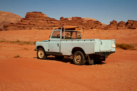A vintage turquoise colored pick up truck is abandoned on red sands of the Wadi Rum desert. This is...