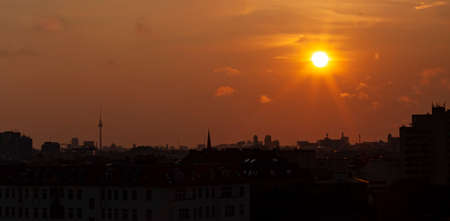 A sunset, sunrise panoramic view of Berlin Skyline featuring silhouettes of landmarks including skyscrapers and the famous Fernsehturm television tower.の写真素材