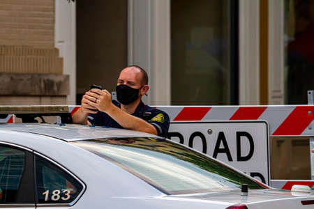 Frederick, MD, USA 08/14/2020: A young caucasian male police officer is wearing a face mask while on...