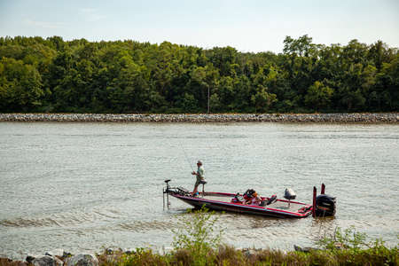 Chesapeake City, MD, USA 08/25/2020: An elderly couple is seen on a red Phoenix bass fishing boat in Chesapeake and Delaware canal. Woman is moving the boat while man is fishing on deck.のeditorial素材