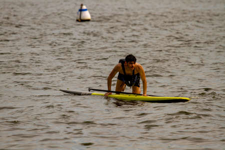 Annapolis, MD 08/21/2020: A young inexperienced kayaker is trying to climb back up to his stand up...