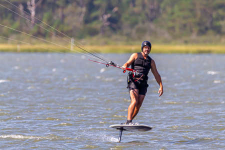 Assateague Island, MD, USA 09/05/2020: A professional kite surfer is on his kite board off the coast of Assateague island. He is surfing with full protective gear on.のeditorial素材