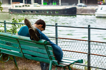 Paris/France 06/13/2010: A close up image of a man sitting on a bench with his  lover lying on his lap The girl is out of the frame and we only see the feet over the top of the bench.のeditorial素材