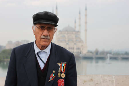 Adana, Turkey 12/26/2009: Portrait of an elderly Turkish man, a veteran of the Korean war, on the historic roman bridge over Seyhan river. He decorates his chest with medals of bravery.のeditorial素材