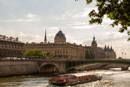 Paris, France, 06/13/2010: A sunny day in Paris. Photo features the river Seine with a sightseeing boat in it, Pont Notre Dame, Conciergerie building, historic courthouse. Sunlight reflects from riverのeditorial素材