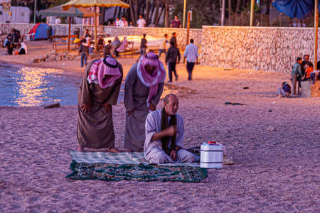 Aqaba, Jordan 03/31/2010: Three Arabic men in ethnic clothes are performing the evening prayer on...