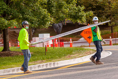 Bethesda, MD, USA 09/15/2020: A caucasian and an African American construction workers are carrying...