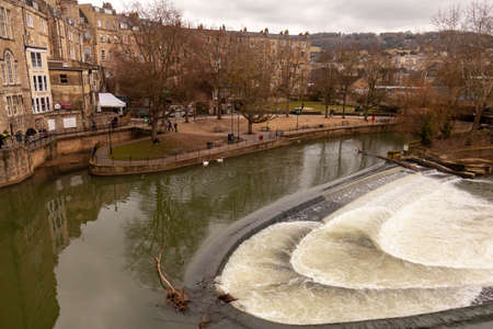 Bath, UK, 03/06/2010: Image of the Avon river in Bath, UK taken from the Pulteney bridge. Image features naked trees, reflection in cascading water, historic buildings and parks.のeditorial素材