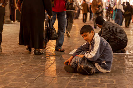 Damascus, Syria 03/28/2010: An Arabic boy is sitting on the floor of Al hamidiyah souq (a crowded...