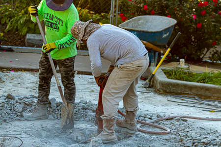 Frederick, MD, USA 10/13/2020: Two construction workers are drilling the concrete floor of a section...