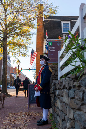 Alexandria, VA, USA 11-28-2020: An employee working at the visitor center of touristic historic Alexandria is waiting outdoor with a minuteman costume. He wears face mask due to COVID-19 pandemic.のeditorial素材