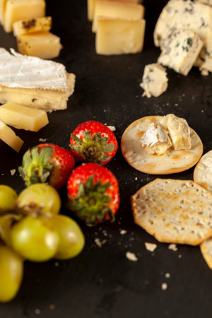 A vertical image of a cheese platter containing a selection of aged artisan French, Italian and...