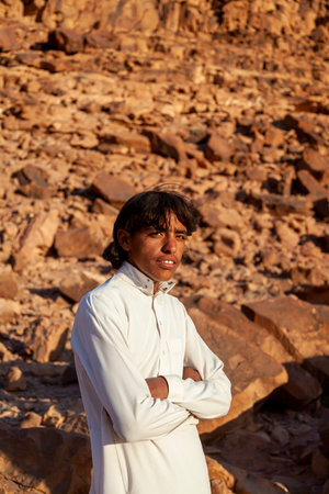 Wadi Rum, Jordan 03.31.2010: A young bedouin man wearing long white jubba thobe dress and standing...
