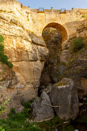 Low angle view of the historical Puento Nuevo (new bridge) that runs over the narrow gorge created by the GuadalevÃ­n river in Ronda. This is an 18th century stone brick bridge with arches. A sunny dayの写真素材