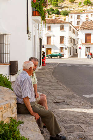 09-07-2010 Ronda, Spain: Two elderly Spanish men are sitting on a stone by a fountain at the town center of the beautiful scenic town. They live a quiet, slow peaceful life. A retirement conceptのeditorial素材