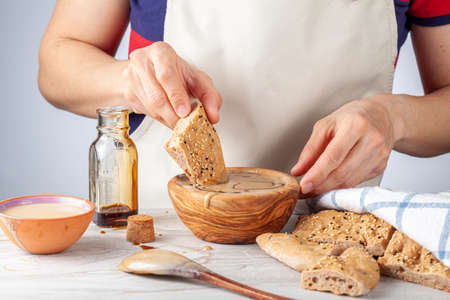 A caucasian woman wearing apron is dipping turkish pide (flat bread) with sesame and poppy seeds...