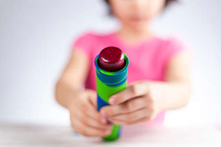 A cute little caucasian girl is squeezing frozen berry sorbet out of the silicon reusable colorful mold. A light and airy background with selective focus to give fairy atmosphere.の写真素材