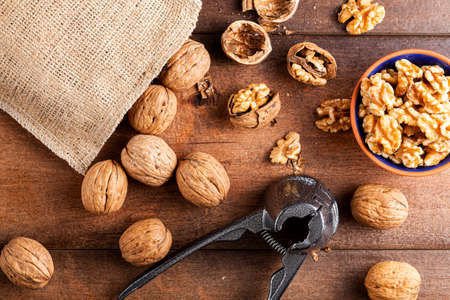Flat lay image showing a cast iron walnut pliers ( a nutcracker tool) with raw fresh walnuts in...