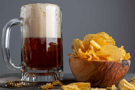 frothy craft beer in glass mug with handle in a pub with dark background. It froths, makes sparkles,...