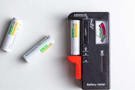 A black plastic battery tester with a clamp on the side that different types of batteries can be inserted so that their charge levels can be measured. Thel level is displayed on the side with a needleの写真素材