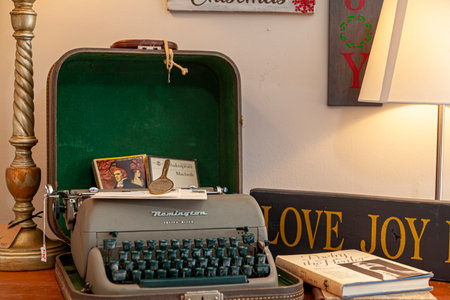 Clifton, VA , USA 11-14-2020: A stylish office decor with a green and gray antique Remington letter ritter model typewritter with its caseand a few hard cover books scattered on a study desk.のeditorial素材