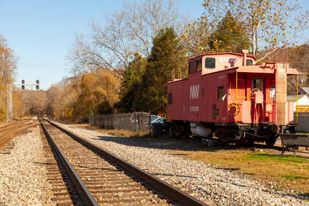 Clifton, VA, USA 11/14/2020: View of the train tracks, ballast, track sleepers and an abandoned red caboose passenger train cabin in front of historic Devereux Station in scenic Clifton Virginia.のeditorial素材