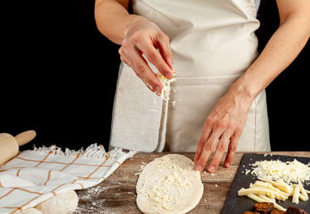 a flattened dough on wood kitchen countertop. A bread making concept image with loafs,  cheese and...