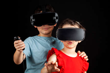 A caucasian boy and a girl wearing virtual reality headsets are playing multiplayer game. A...