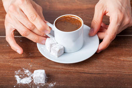 A caucasian Turkish woman is drinking traditional Turkish coffee from special cup. The coffee is served with Turkish delight  on the side of the plate. Close up concept image.の写真素材