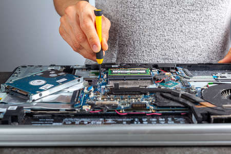 A computer technician is repairing an old laptop using a screw driver. Closeup isolated image...