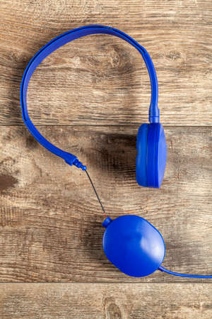 Isolated image of a blue headphone with adjustable head band. One of the ear pieces is broken at the...