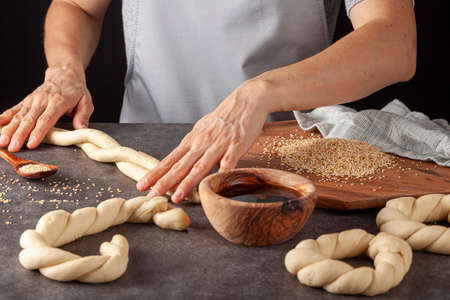 delicious Turkish bagel with sesame seeds known as susamli simit.  A woman is making twisted rolls...