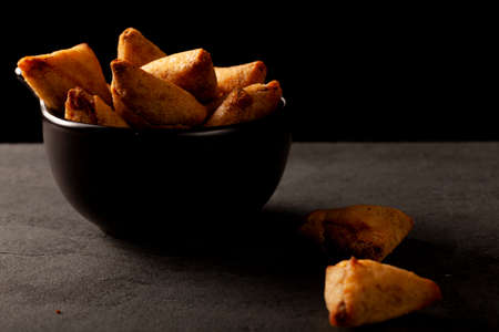 Dark background low light image showing a closeup view of traditional indian samosa, a fried...