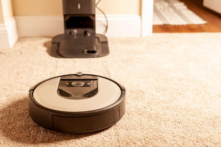 Close up generic image for robot vacuum cleaner. This unit is operating on carpetted floor and heading towards its base station for charging and emptying its bag. A convenient home automationの写真素材