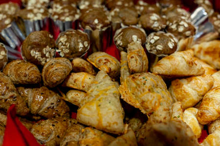 A bunch of sampling size pastries offered at a cocktail buffet in a party. There are whole wheat alternatives, croissants and cheese pastries as well as muffinsの写真素材