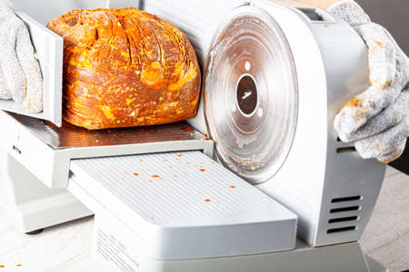 Close up isolated image showing a butcher or chef slicing a large frozen cured meat block. Turkish pastirma, pastrami, ham, beef concept. The person wears protective cut resistant glovesの写真素材