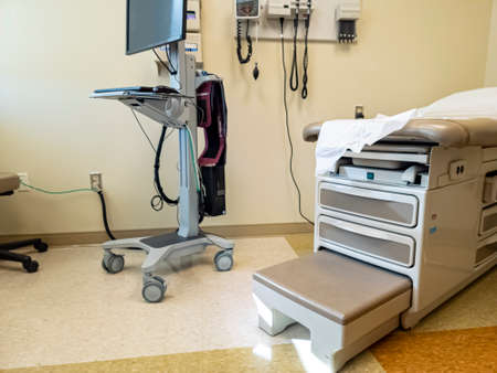 Inside of an empty exam room with a bed, some medical devices, a computer. Generic concept image for...