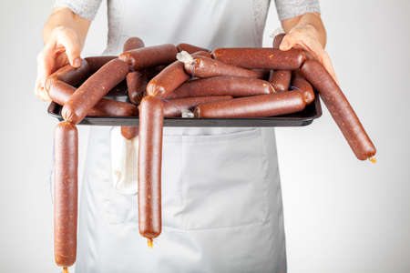 A woman chef is showing a heap of homemade Turkish sucuk or sausage on a tray. Processed fermented spicy red meat consumption concept.の写真素材