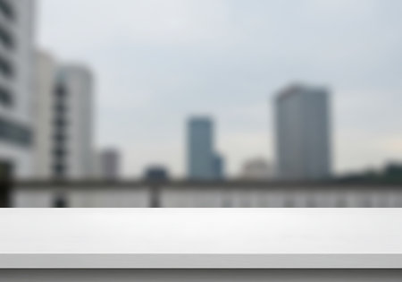 A soft focus view of tall buildings and a body of water with a clean white surface in the foreground.の素材