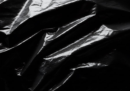 A high contrast, abstract image revealing the intricate details and textures of a dark, crinkled material.の素材