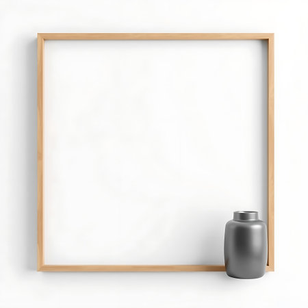 A simple wooden square frame sits on a white surface next to a small, dark, rounded vase.の素材
