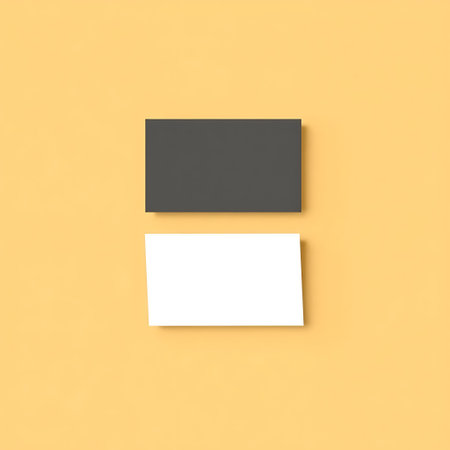 A top down view of two rectangular cards, one dark gray and one white, placed on a soft yellow surface.の素材