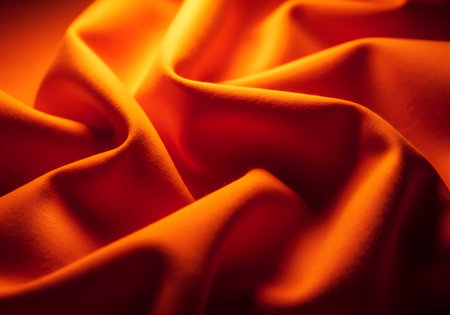 Close-up view of flowing orange textile with deep shadows and bright highlights, creating a sense of movement and texture.の素材