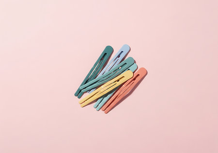 A collection of pastel colored clothes pins are neatly arranged on a soft pink surface, creating a charming and clean aesthetic.の素材