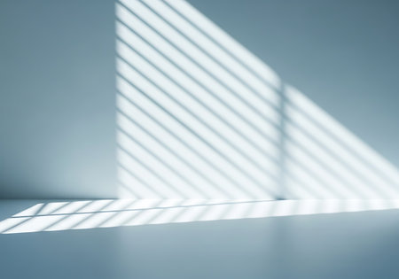 Abstract pattern of light and shadow created by window blinds on a minimalist, cool-toned interior surface.の素材
