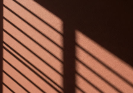 Abstract pattern of diagonal light and shadow stripes on a warm, textured background, creating a minimalist aesthetic.の素材